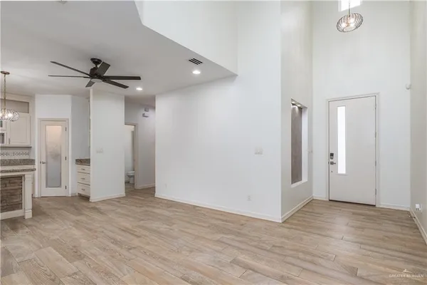 an empty room with wooden floor and a ceiling fan