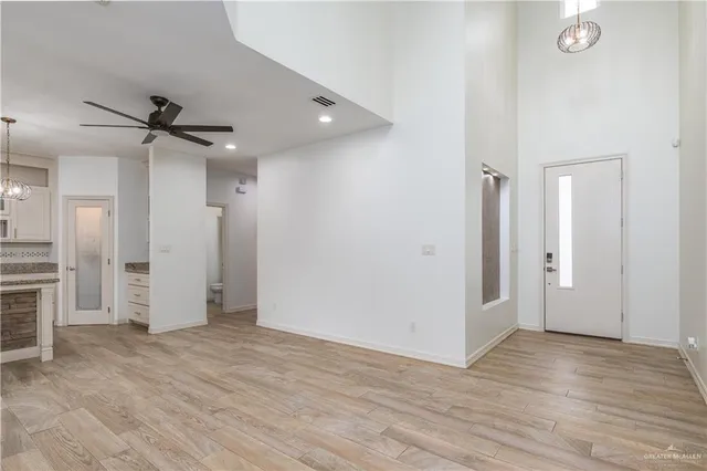 an empty room with wooden floor and a ceiling fan