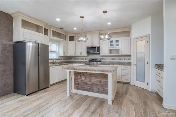 a large kitchen with cabinets a sink dishwasher a refrigerator and a fireplace