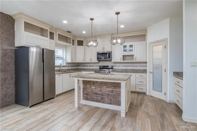 a large kitchen with cabinets a sink dishwasher a refrigerator and a fireplace