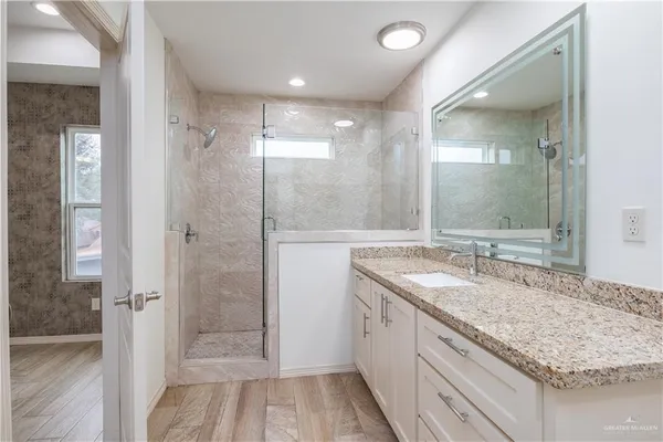a bathroom with a granite countertop sink mirror and shower