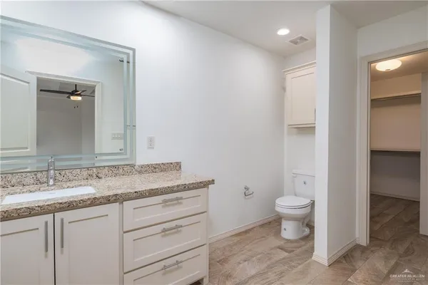 a spacious bathroom with a granite countertop sink a toilet and a mirror
