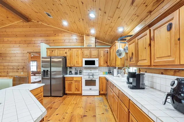 a living room with stainless steel appliances kitchen island granite countertop a table chairs and a wooden floor