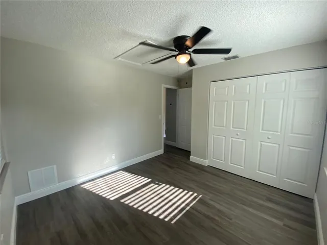 an empty room with wooden floor fan and windows