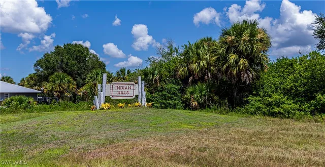 a sign of golf club on a wall under a large tree