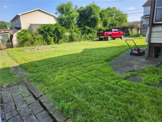 a view of a fire pit in front of a brick house with a small yard