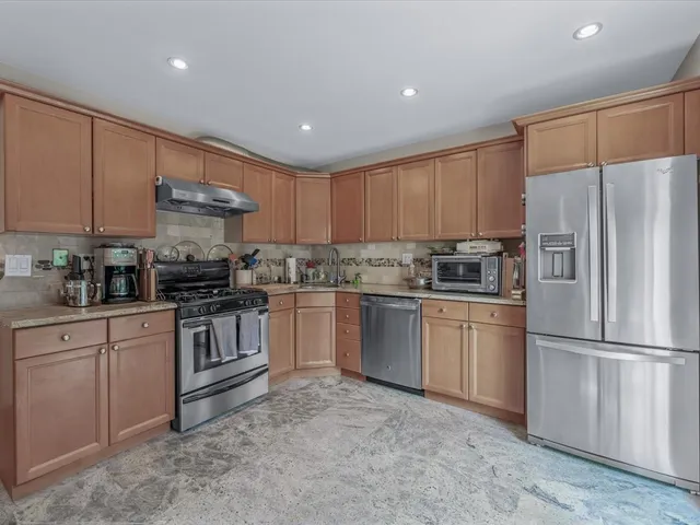 a kitchen with granite countertop a refrigerator sink and cabinets