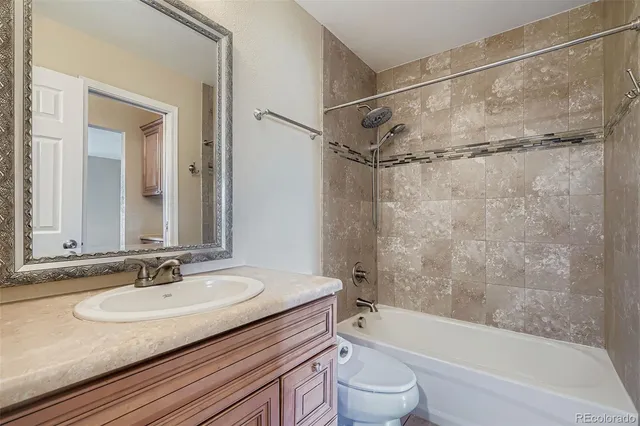 a bathroom with a granite countertop sink a toilet and shower