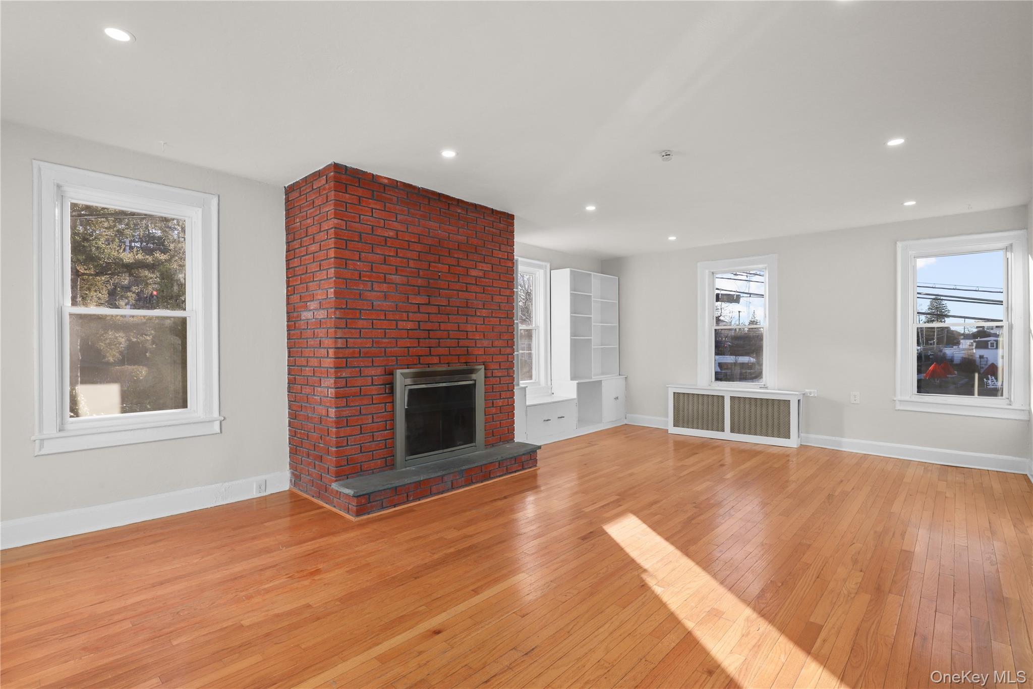 8 Virginia Avenue, Unit 1 Dobbs Ferry, NY 10522 - Photo 3 of 15 Unfurnished living room featuring light wood-type flooring, a fireplace, radiator heating unit, and recessed lighting