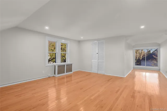 a view of an empty room with window and wooden floor