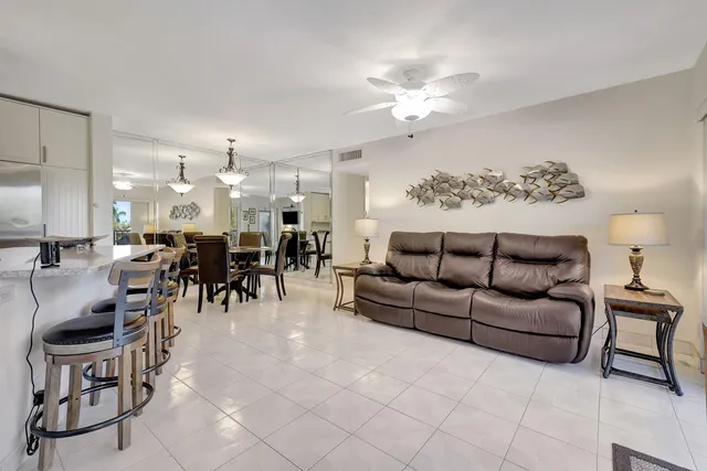 a living room with furniture kitchen view and a chandelier