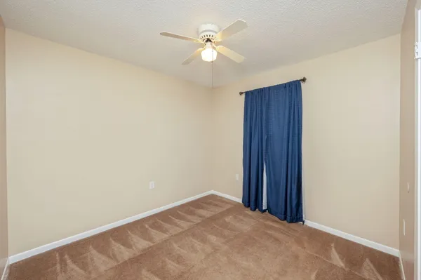 an empty room with closet and a ceiling fan