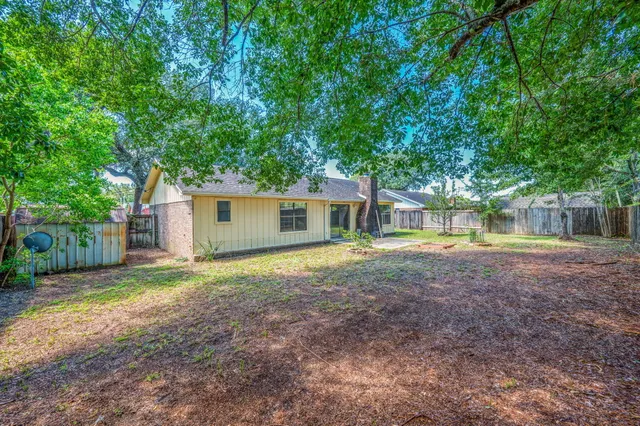 a view of a house with a yard and large tree