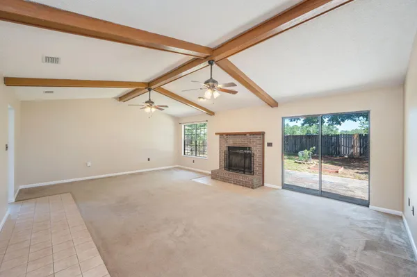 a view of empty room with floor to ceiling window and fireplace