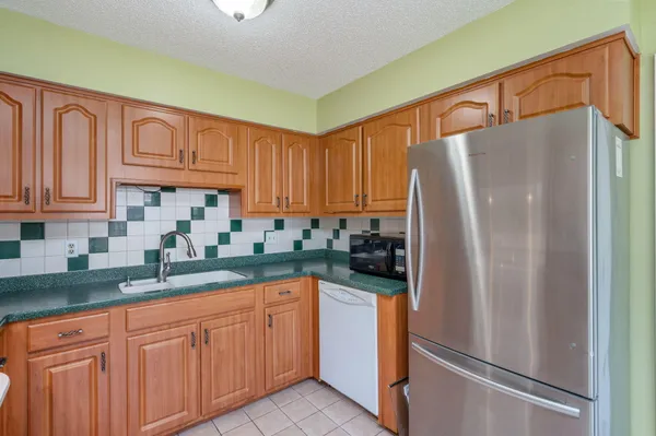a kitchen with granite countertop a refrigerator a sink and cabinets