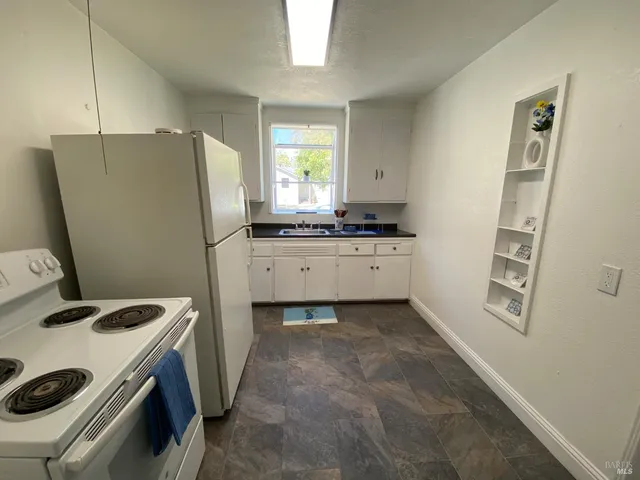a white refrigerator freezer and a stove sitting inside of a kitchen
