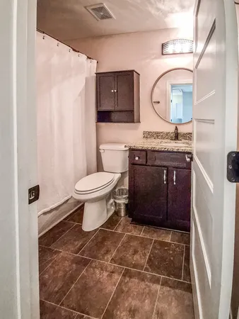 a bathroom with a granite countertop toilet sink and mirror