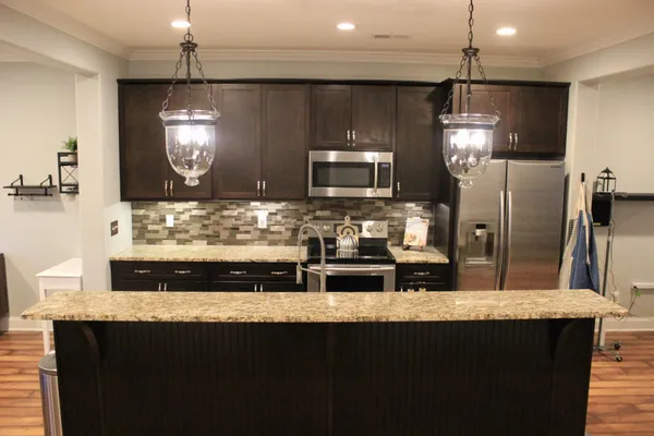 a kitchen with kitchen island granite countertop a sink stainless steel appliances and cabinets