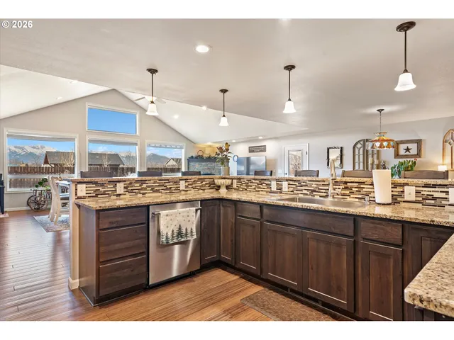 a kitchen with stainless steel appliances granite countertop a sink a stove and a wooden floors