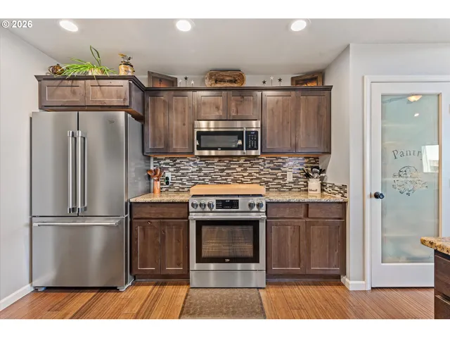 a kitchen with granite countertop a refrigerator and a stove top oven