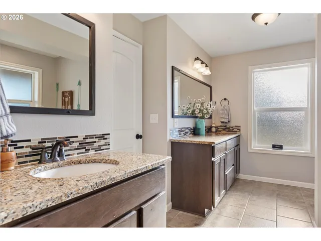 a bathroom with a granite countertop double vanity sink and mirror