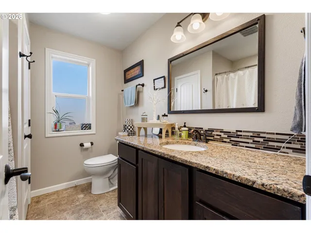 a bathroom with a granite countertop toilet sink and mirror