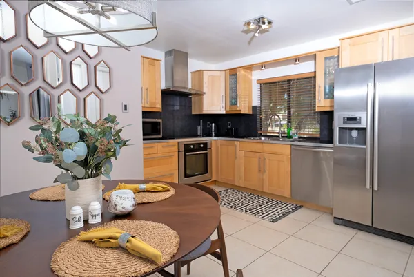 a kitchen with stainless steel appliances a sink a counter top space cabinets and a dining table
