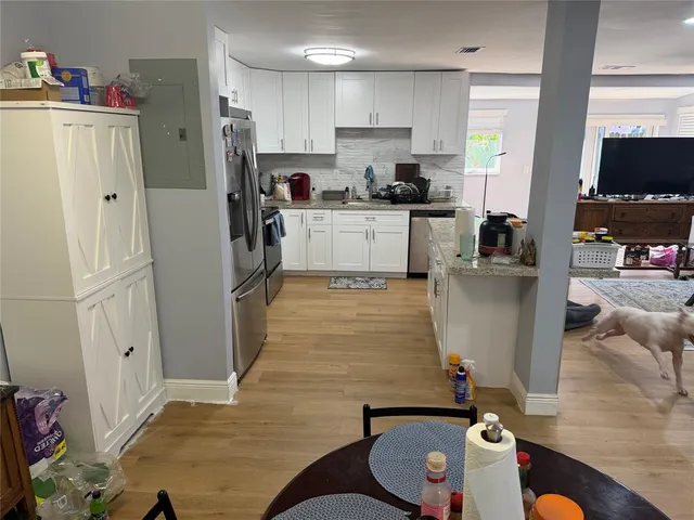 a kitchen with stainless steel appliances granite countertop a refrigerator sink and white cabinets