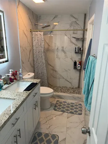 a bathroom with a granite countertop sink toilet and shower