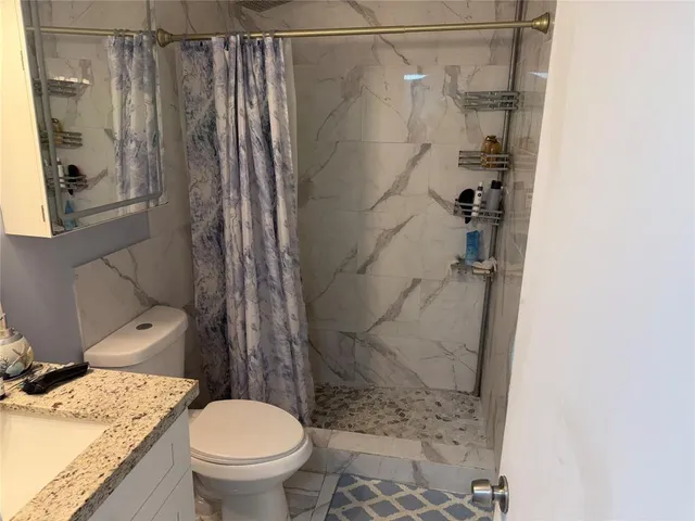 a bathroom with a granite countertop sink toilet and shower