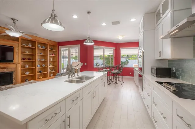 a kitchen with stainless steel appliances a large counter top a stove a chimney a sink and a large window