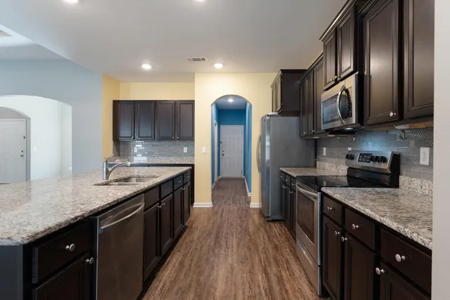 a kitchen with stainless steel appliances granite countertop a stove a sink and a refrigerator