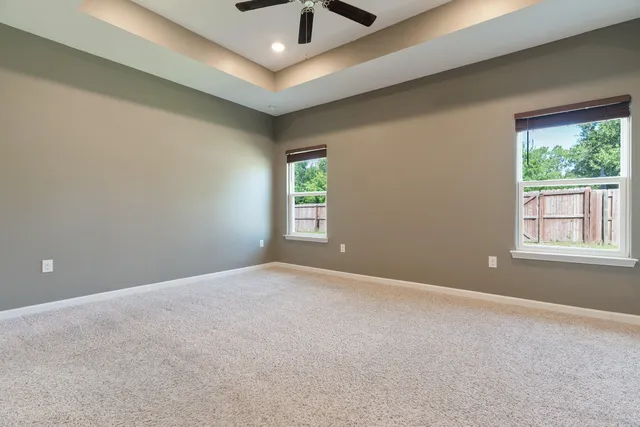 an empty room with windows and ceiling fan