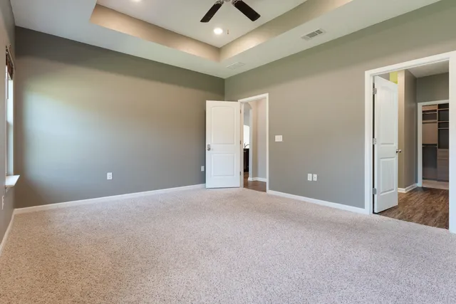 a view of an empty room and chandelier fan