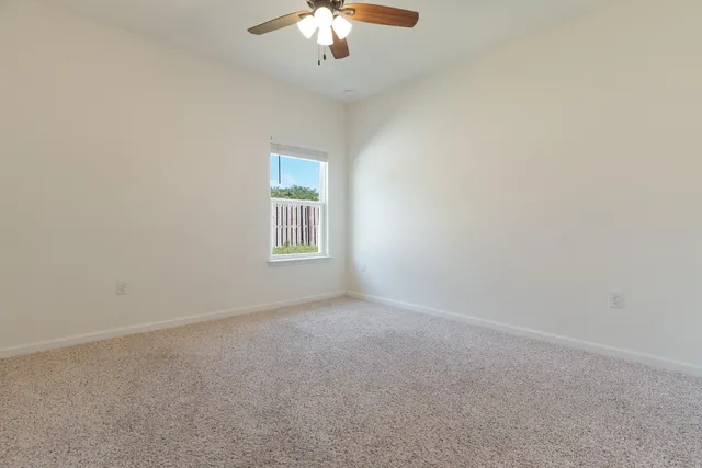 a view of an empty room and chandelier fan