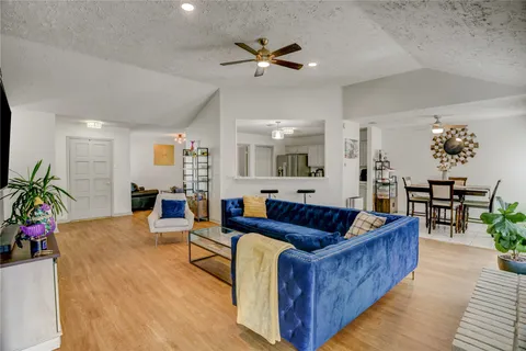 a living room with furniture kitchen view and a chandelier