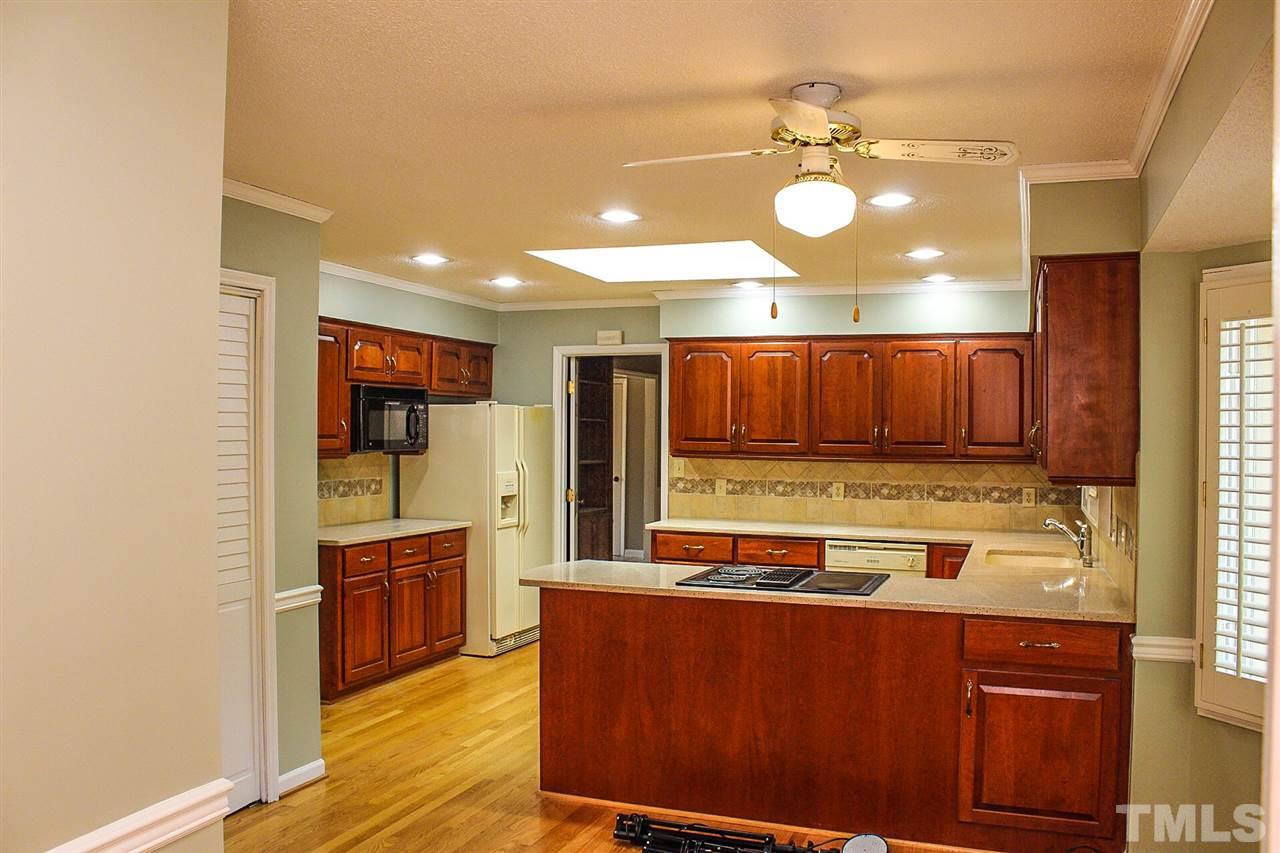 9444 Springdale Drive Raleigh, NC 27613 - Photo 5 of 25 a kitchen with wooden cabinets and stainless steel appliances