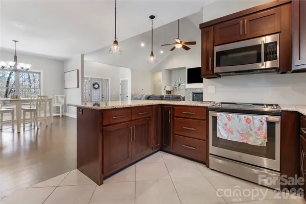 a kitchen with stainless steel appliances granite countertop a stove a microwave and wooden cabinets