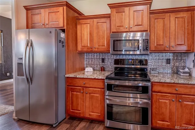 a kitchen with granite countertop a refrigerator stove and cabinets