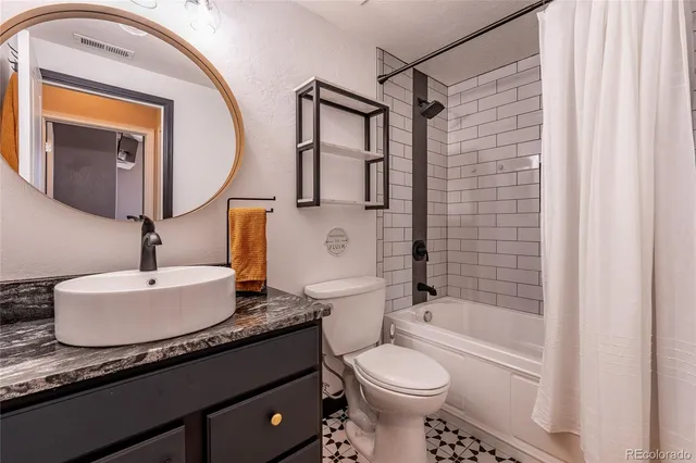 a bathroom with a granite countertop sink mirror vanity and toilet