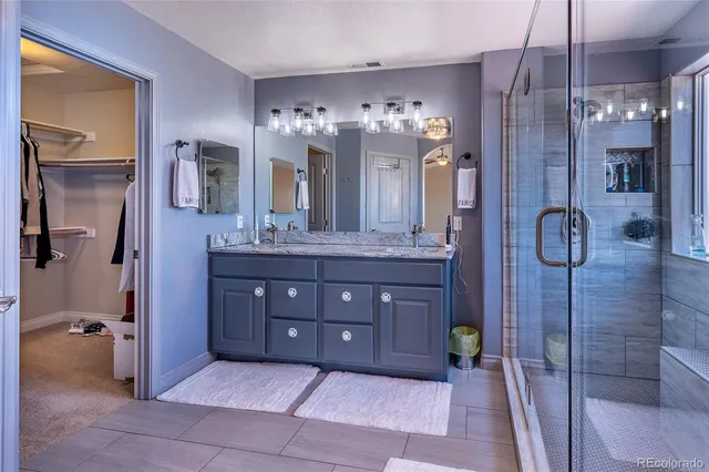 a bathroom with a granite countertop sink a mirror and a shower