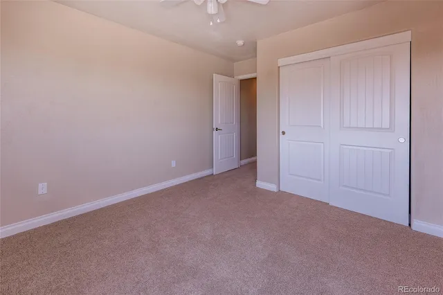 a view of an empty room and chandelier fan