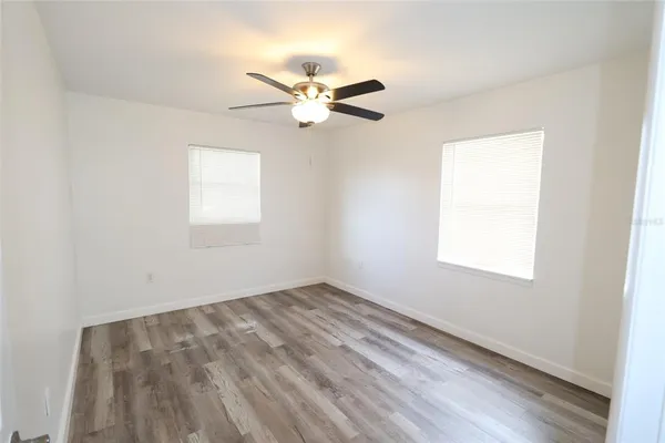 an empty room with windows and fan