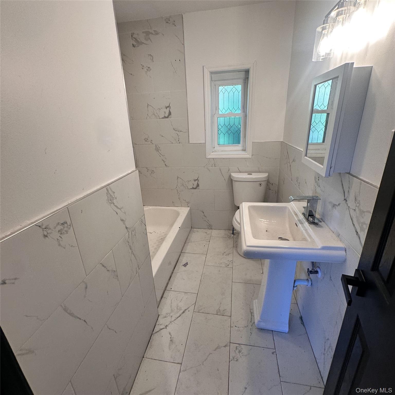 152 Smith Street, Unit 2 Poughkeepsie, NY 12601 - Photo 8 of 8 Ceramic floors and walls, pedestal sink, medicine cabinet, toilet.