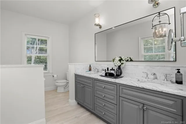 a bathroom with a granite countertop sink a toilet and with mirror
