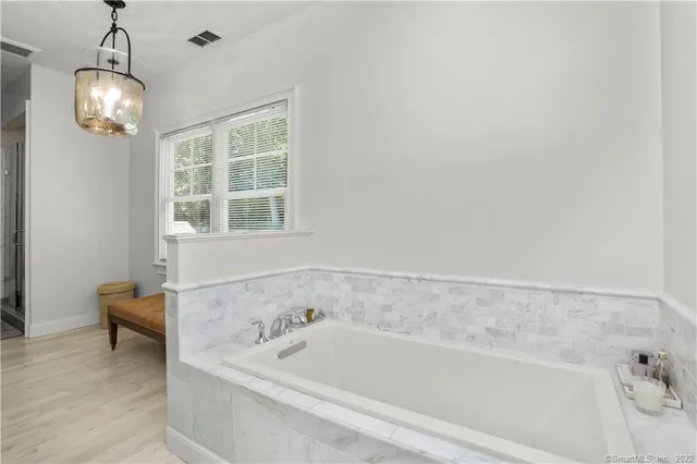 a bathroom with a bathtub and chandelier
