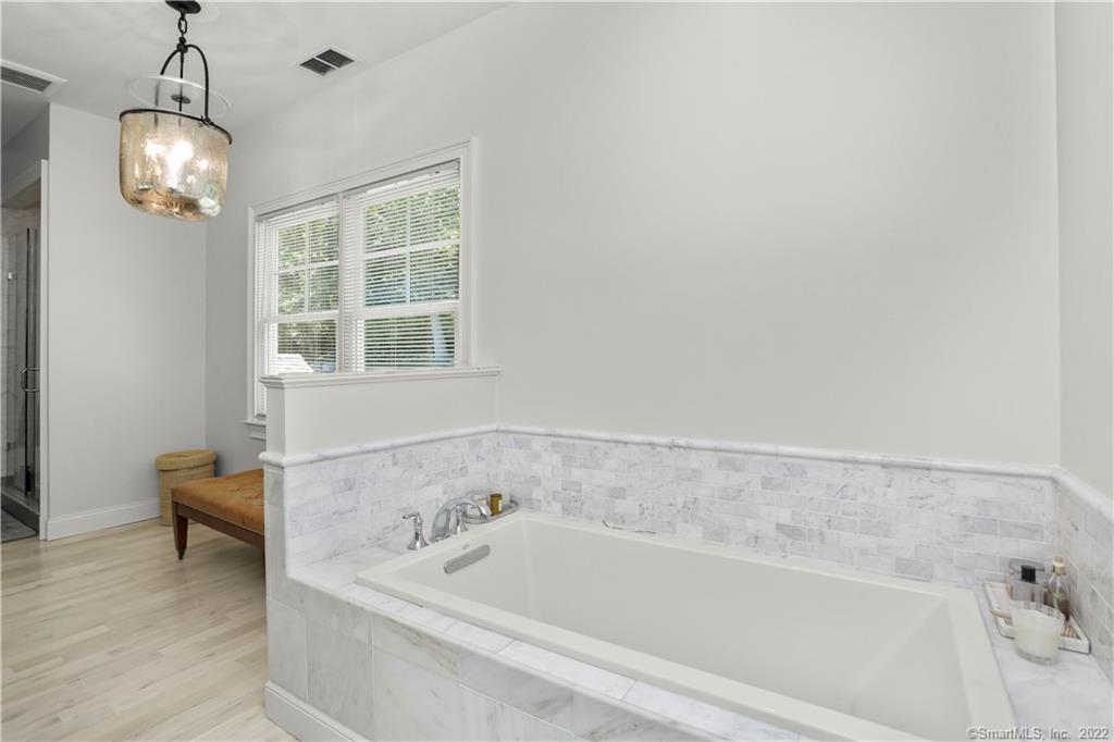220 Burr Street Fairfield, CT 06824 - Photo 18 of 34 a bathroom with a bathtub and chandelier
