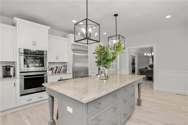 a kitchen with stainless steel appliances kitchen island granite countertop a stove a refrigerator and a wooden floor