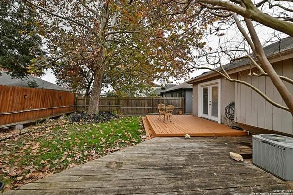 a backyard of a house with wooden fence and large trees
