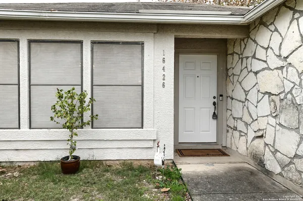 a white house with a yard and plants